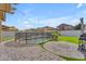 Backyard pool enclosed with a fence, surrounded by artificial turf, palm trees, and paved areas at 14875 W Larkspur Dr, Surprise, AZ 85379