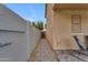 A narrow side yard with a concrete wall, a gravel path, a wooden gate, and the side of the house at 14875 W Larkspur Dr, Surprise, AZ 85379