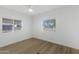 Bright bedroom featuring wood-look floors, a ceiling fan, and two windows offering ample natural light at 16215 N 35Th Pl, Phoenix, AZ 85032