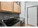 Modern laundry room features sleek gray machines, ample cabinet storage, and stylish dark backsplash at 1785 S 222Nd Ln, Buckeye, AZ 85326