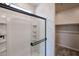 Bathroom with glass shower doors and open closet for storage at 18243 W Daley Ln, Surprise, AZ 85387