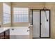 Bright bathroom featuring a large bathtub, glass-enclosed shower, and a privacy window at 2280 E Aloe Pl, Chandler, AZ 85286
