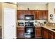 A kitchen features a black oven and microwave, as well as dark wood cabinets and a granite countertop at 2280 E Aloe Pl, Chandler, AZ 85286