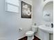 Clean half-bathroom with a pedestal sink, toilet, framed art, round mirror and wood-look floors at 2315 N 73Rd Dr, Phoenix, AZ 85035