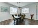 A cozy dining room with a rustic wood table, six upholstered chairs, and natural light from the large window at 2315 N 73Rd Dr, Phoenix, AZ 85035