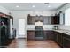 A well-lit kitchen featuring dark wood cabinets, stainless steel appliances, granite countertops, and wood floors at 2315 N 73Rd Dr, Phoenix, AZ 85035