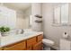 Bathroom featuring a wood cabinet sink, an above sink mirror, and adjacent toilet with a window at 26015 S Grapefruit Dr, Queen Creek, AZ 85142