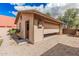 Garage featuring an open garage door, tan wooden siding, adjacent to a lawn and gravel at 26015 S Grapefruit Dr, Queen Creek, AZ 85142