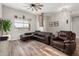 Comfortable living room with hardwood floors, brown leather couches, and a ceiling fan at 26015 S Grapefruit Dr, Queen Creek, AZ 85142