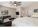 Comfortable main bedroom featuring a ceiling fan, view of the bathroom, and a leather sofa at 26015 S Grapefruit Dr, Queen Creek, AZ 85142
