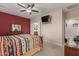 Bright bedroom featuring a ceiling fan, red accent wall, dresser with mirror, and a mounted TV at 30444 N Bismark St, San Tan Valley, AZ 85143