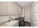 Laundry room with gray cabinets, stainless steel washer/dryer, gray counters, and decorative backsplash at 6166 N Scottsdale Rd # C4004, Paradise Valley, AZ 85253