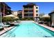 Community pool with clear water, lounge chairs, umbrellas, cabanas, and multi-story buildings at 6166 N Scottsdale Rd # C4004, Paradise Valley, AZ 85253