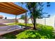 Lush backyard featuring mature trees, green grass, block fence, and a covered patio at 7056 W Caron Dr, Peoria, AZ 85345