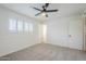 Bright bedroom with neutral carpet, ceiling fan, and large windows for natural light at 7145 E Baywood Ave, Mesa, AZ 85208