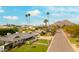 Charming home with a well-maintained lawn, a stone-accented facade, and palm trees lining the street with mountain views at 7417 E Bonita Dr, Scottsdale, AZ 85250