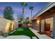 Backyard with a putting green, desert landscaping, patio, and seamless indoor-outdoor living with a glass door at 9088 E Winchcomb Dr, Scottsdale, AZ 85260