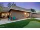 Wide angle view of a backyard with a putting green, patio, and desert landscaping on a twilight evening at 9088 E Winchcomb Dr, Scottsdale, AZ 85260