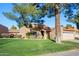 Inviting home with a red tile roof, lush green lawn, manicured shrubbery, and mature shade tree at 9088 E Winchcomb Dr, Scottsdale, AZ 85260