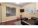 Small and cozy living room with wood floors, a leather sofa, and a mounted TV at 9088 E Winchcomb Dr, Scottsdale, AZ 85260