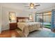 Comfortable main bedroom with ceiling fan, wood floors, and a sliding glass door leading to the yard at 9088 E Winchcomb Dr, Scottsdale, AZ 85260