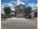 Charming two-story home featuring a two-car garage, manicured trees, and beautiful blue skies at 9207 W Sells Dr, Phoenix, AZ 85037