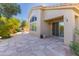 An inviting back patio with stone tiling leads to the house with large windows and outdoor cooking space at 9475 N 115Th Pl, Scottsdale, AZ 85259
