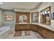 Luxurious bathroom featuring wood cabinets, granite counters, tub and decorative mirrors at 10567 E Fernwood Ln, Scottsdale, AZ 85262