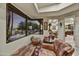 Comfortable living space showcasing a plush leather couch, patterned ottomans, and large windows overlooking the pool at 10567 E Fernwood Ln, Scottsdale, AZ 85262