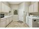 Well-lit laundry room features ample cabinet space, white appliances, and neutral tile flooring at 11216 E Appaloosa Pl, Scottsdale, AZ 85259