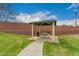 Community picnic area with metal table and grill surrounded by lush green grass and a brick privacy wall at 121 N Ramada --, Mesa, AZ 85205