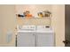 Well-lit laundry room featuring a white washer and dryer set and shelving for storage at 16157 W Moreland St, Goodyear, AZ 85338