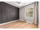 Bedroom featuring wood floors, a dark accent wall, and a large window with draperies for natural light at 1827 S 237Th Dr, Buckeye, AZ 85326