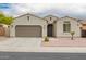 Close up of single-story home with neutral paint, well-manicured front yard and two car garage at 1827 S 237Th Dr, Buckeye, AZ 85326