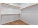 A simple walk-in closet with white walls, wood floors, and rods for hanging clothes at 1827 S 237Th Dr, Buckeye, AZ 85326