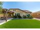 A backyard featuring a well-maintained lawn, covered patio, and desert landscaping provides a serene outdoor living space at 19740 W Sherman St, Buckeye, AZ 85326