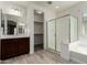 Well-lit bathroom featuring a glass-enclosed shower, tub, dual sinks, and a walk-in closet at 19740 W Sherman St, Buckeye, AZ 85326