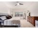 Bright primary bedroom with a large window, neutral carpet, ceiling fan, and dark wood dresser at 27878 N 175Th Dr, Surprise, AZ 85387