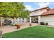 Landscaped backyard with artificial turf, brick patio, seating area, and a distant view of the pool at 3522 E Fountain St, Mesa, AZ 85213