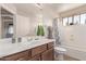 Well-lit bathroom with a wooden vanity, a shower-tub combo, and a large mirror at 41838 W Anne Ln, Maricopa, AZ 85138