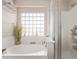 Bright bathroom with a soaking tub and shower, accented by a unique glass block window at 41838 W Anne Ln, Maricopa, AZ 85138