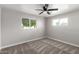 Bright bedroom with neutral carpet, a modern ceiling fan, and windows providing natural light and view of the yard at 4402 E Mitchell Dr, Phoenix, AZ 85018