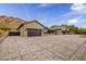 Long shot of an elegant home featuring multiple garages, desert landscaping, and a private gated entrance at 5301 E Paradise Canyon Rd, Paradise Valley, AZ 85253