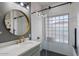 Elegant bathroom featuring modern vanity, large round mirror, and a glass-enclosed shower with unique window at 7420 E Northland Dr # B101, Scottsdale, AZ 85251