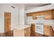 Kitchen showcasing a center island, white appliances, light wood cabinets, and red-tiled floor at 7929 W Wescott Dr, Glendale, AZ 85308