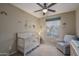 Cozy bedroom with a crib, chair, neutral walls, ceiling fan, and a window at 9547 W Chama Dr, Peoria, AZ 85383