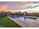 Relaxing backyard pool area with a serene waterfall, lounge chairs, fire pit, and ambient string lights creating an inviting atmosphere at 9547 W Chama Dr, Peoria, AZ 85383