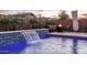 Beautiful backyard pool featuring a modern waterfall and cozy fire pit seating, creating a perfect spot for relaxation and entertaining guests at 9547 W Chama Dr, Peoria, AZ 85383