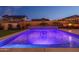 Stunning backyard pool illuminated with vibrant blue lights, complemented by a soothing waterfall and cozy lounge seating, perfect for evening swims at 9547 W Chama Dr, Peoria, AZ 85383