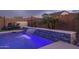 Backyard pool showcasing a modern waterfall feature, comfortable lounge seating, and ambient string lights for a relaxing outdoor experience at 9547 W Chama Dr, Peoria, AZ 85383